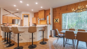 Une cuisine moderne avec des meubles en bois, un réfrigérateur en acier inoxydable et un coin bar avec des tabourets.