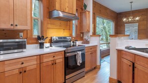 Une cuisine moderne avec des meubles en bois, des appareils électroménagers en acier inoxydable et une grande fenêtre qui laisse entrer la lumière naturelle.