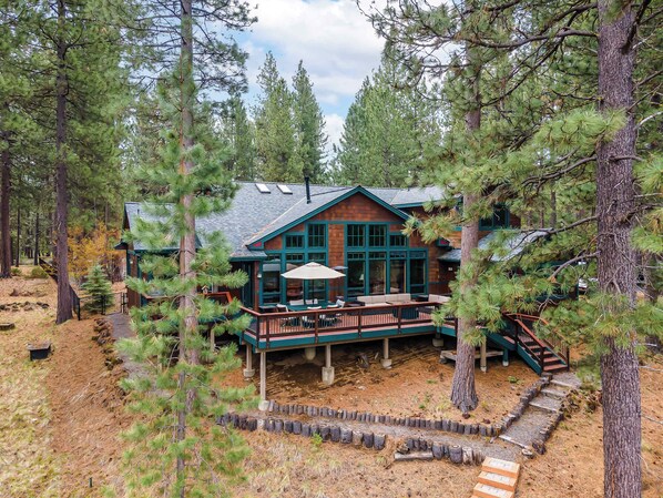 A cabin with a deck, surrounded by trees.