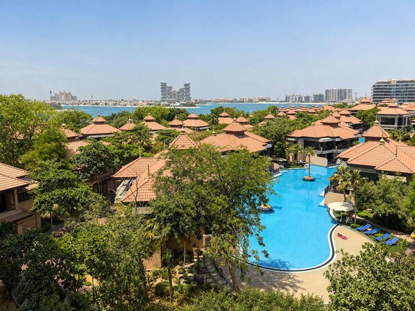 A resort with a central swimming pool surrounded by villas with red-tiled roofs.