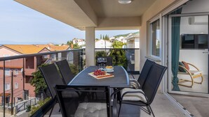 Ein Balkon mit Tisch für zwei Personen, gedeckt mit einem Teller Trauben und einem Glas Rotwein.