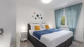 Ein Schlafzimmer mit einem Bett, einem Nachttisch, einer Lampe und einem Sessel.