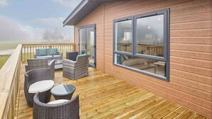 A wooden deck with wicker furniture and glass doors leading to an interior. - Host Stay Linden Lodge Ashdown Retreat (Pickering)