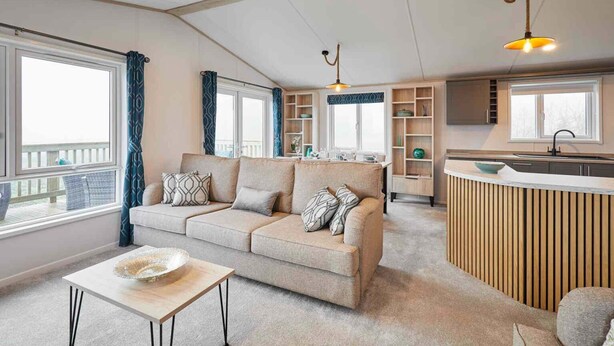 A modern living room with a sofa, a coffee table, and a kitchen area with a counter and shelves. - Host Stay Linden Lodge Ashdown Retreat (Pickering)