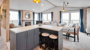 A modern kitchen with a central island, bar stools, and a dining area with a table set for four. - Host Stay Linden Lodge Ashdown Retreat (Pickering)