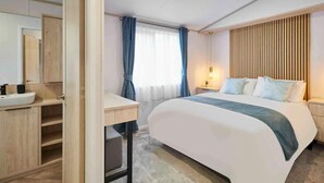 A modern hotel room with a bed, bedside table, lamp, and a bathroom with a sink and mirror. - Host Stay Linden Lodge Ashdown Retreat (Pickering)