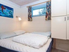 A room with a bed, a window with curtains, a wall-mounted light, and a painting. - 6 Person Holiday Home in Herning (Herning)