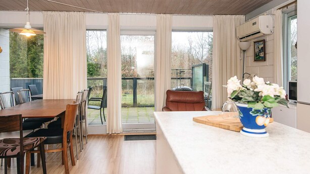 A modern kitchen with a dining area, large windows, and a view of the backyard. - 6 Person Holiday Home in Herning (Herning)
