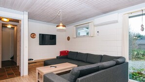 A modern living room with a grey sectional sofa, a wooden coffee table, and a flat-screen TV mounted on the wall. - 6 Person Holiday Home in Herning (Herning)