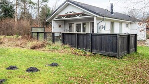 A single-story house with a white exterior, a dark wooden fence, and a grassy yard. - 6 Person Holiday Home in Herning (Herning)