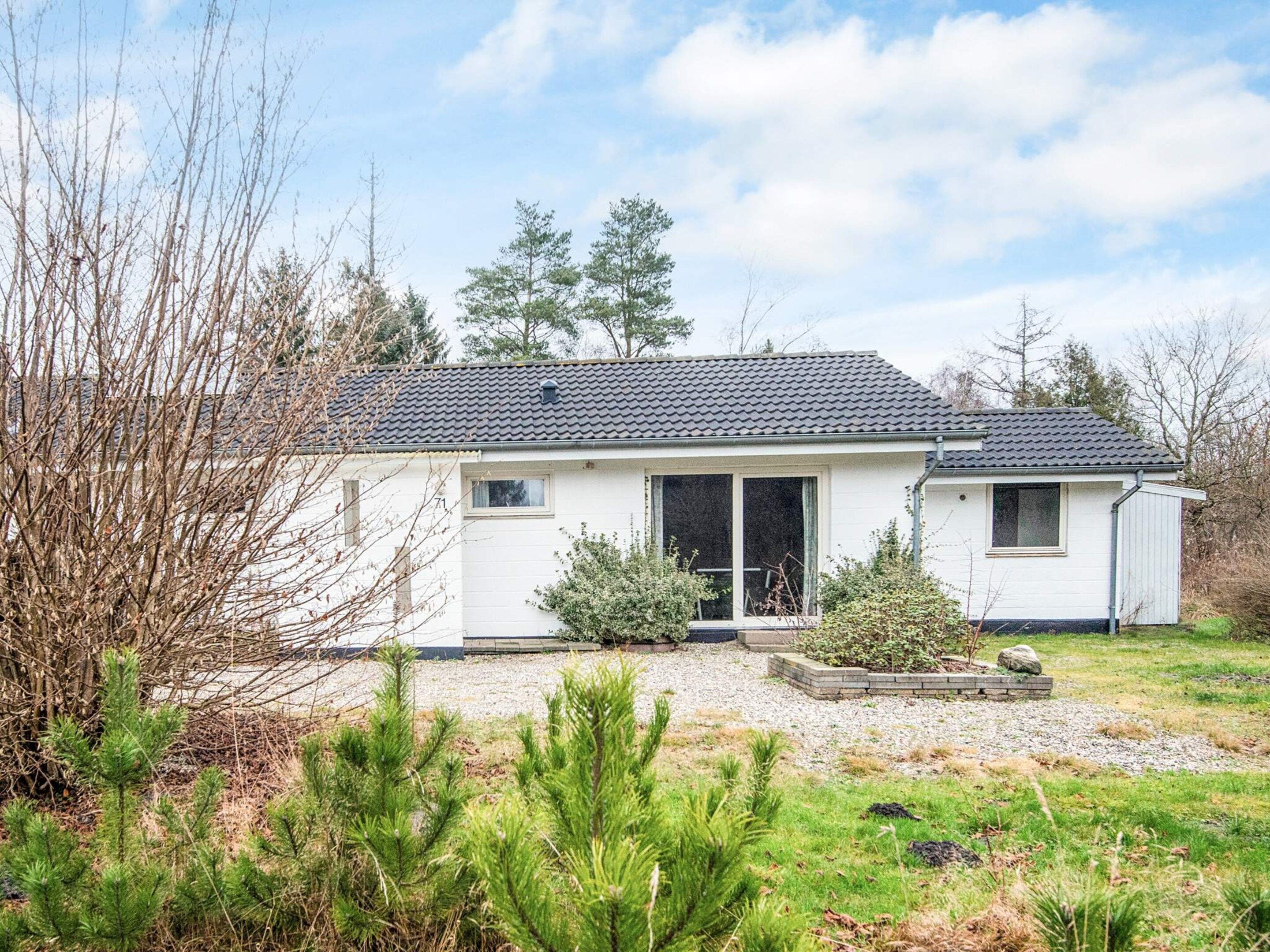 A single-story house with a tiled roof, a front porch, and a small garden area.