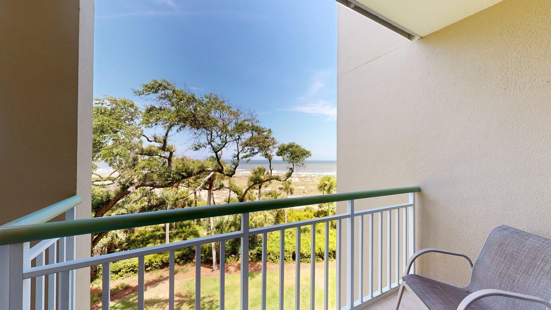 En balkon med udsigt over stranden og træerne.