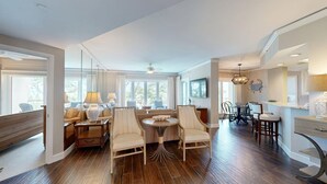Un vaste espace de vie comprenant une grande table à manger, des sièges confortables et un coin cuisine avec un bar.