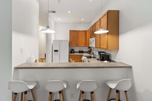 Una cocina moderna con armarios de madera, una isla central con taburetes altos e iluminación colgante.