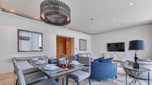 A modern living room with a dining area, a TV, and a chandelier. - bnbme | Damac Resi (Riyadh)
