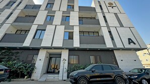 A modern building with a prominent 'A' sign, featuring a clean, geometric facade with balconies and a flat roof. - bnbme | Riviera-A5 | 3 Bdr (Riyadh)
