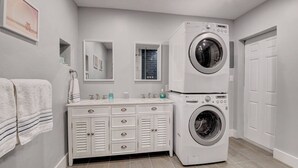 A laundry room with a washing machine, a sink, and a vanity with drawers. - Coastal Cottage private oasis w/ Hot Tub & less than 5 minutes to beach! (Boynton Beach)