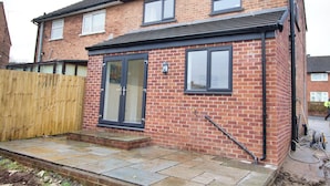 A two-story brick house with a front door, windows, and a wooden fence. - 3 Bed, Sleeps 5, Pet Friendly, Free Parking (Mexborough)