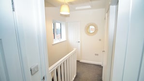 A narrow hallway with white walls, a white door, a window, a mirror, and a light fixture. - 3 Bed, Sleeps 5, Pet Friendly, Free Parking (Mexborough)