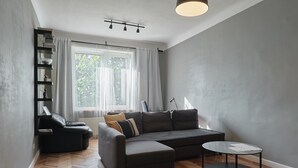 Un salon moderne avec un canapé gris, une petite table ronde et une bibliothèque.