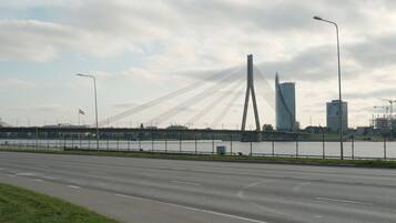 Un pont moderne avec des câbles, une rivière et des bâtiments urbains en arrière-plan.