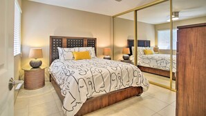 Een slaapkamer met een bed, nachtlampjes, een spiegel en een plafondventilator.