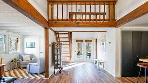 A spacious living room with hardwood floors, a staircase, and a view of the outdoors.