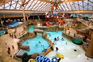 Parque acuático interior con varias piscinas, toboganes y zonas de juegos de agua.