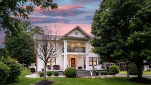A two-story house with a front porch, a small garden, and a well-maintained lawn.