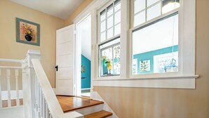 A staircase with white railings and wooden steps leading to a room with teal walls and a window with a view.