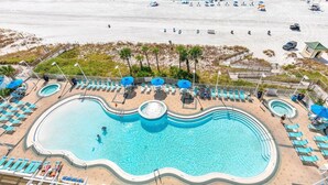 Un resort con una piscina grande, acceso a la playa y tumbonas.