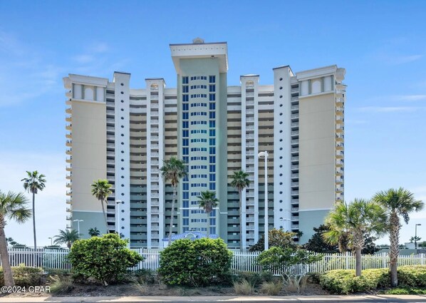 A multi-story hotel with a central atrium, balconies on each floor, and palm trees in the foreground. - 6th Floor @ The Boardwalk, Directly on the Beach! Sleeps 6 (Panama City Beach)