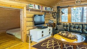 A cozy cabin interior with a wooden interior, a sofa, a coffee table, a bookshelf, and a television. - Peurakangasranta 4 * luxury logcabin in Ranua, lakeside in the forest with AC (Lappi)