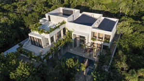 Een modern huis met een zwembad, omringd door weelderige begroeiing.