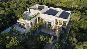 Een modern huis met een zwembad, omringd door weelderige begroeiing.