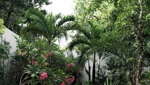 Een tuinpad met stapelen stenen dat door weelderig groen en bloeiende planten leidt.