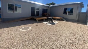 A two-story building with a covered patio area, a barbecue grill, and a small table.
