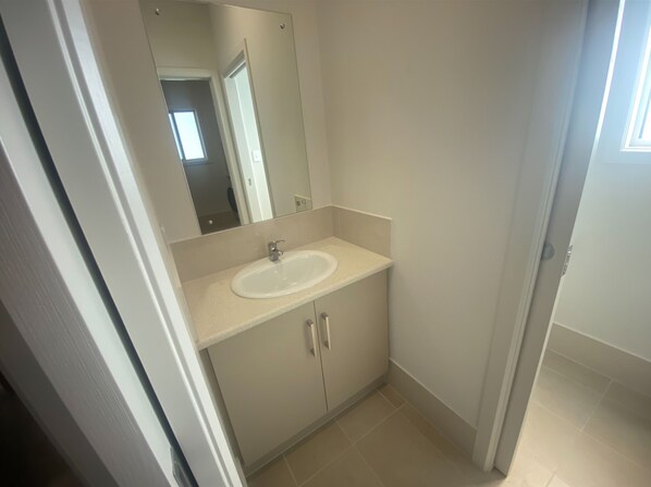 A bathroom with a white sink, a mirror, and a door leading to another room.