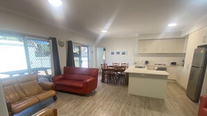 A modern living room with a red sofa, a brown leather sofa, and a dining area with wooden chairs and a table.