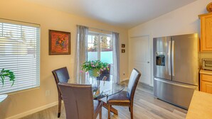 A modern kitchen with a stainless steel refrigerator, a dining area with a glass table and leather chairs, and a window with blinds. - ~ 3 Mi to Ski & Hiking Trails: Soldotna Home (Soldotna)