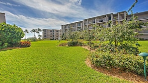 A hotel with a well-maintained lawn, multiple balconies, and a clear sky.