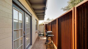Une terrasse avec un barbecue, une porte et une clôture.