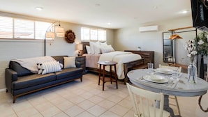 Une chambre moderne et bien éclairée, avec un lit, une table de chevet et un coin repas avec une table mise pour deux personnes.