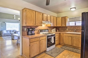 A kitchen with wooden cabinets, a gas stove, a sink, and a refrigerator. - Tranquil Tucson Home w/ Yard - Walk to U of A (Tucson)