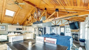 Une cuisine spacieuse équipée d’appareils modernes, un coin repas avec une table en bois et un salon confortable agrémenté d’une cheminée.