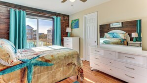 A bedroom with a bed, a dresser, a ceiling fan, and a window with curtains. - Walk to Beach: Duplex in North Topsail Beach! (Sneads Ferry)