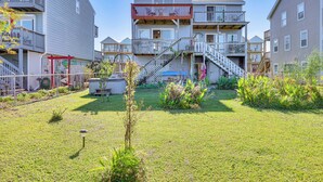 A multi-story residential building with a central staircase, a fenced yard, and a small garden area. - Walk to Beach: Duplex in North Topsail Beach! (Sneads Ferry)