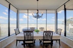 Ein Wintergarten mit Tisch und Stühlen, einer Kandelaber und Blick auf den Strand.