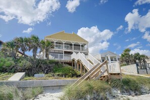 A beachfront property with a two-story structure, a balcony, and a staircase leading to the upper level. - Oceanfront Escape on Wilbur Beach! (Port Orange)