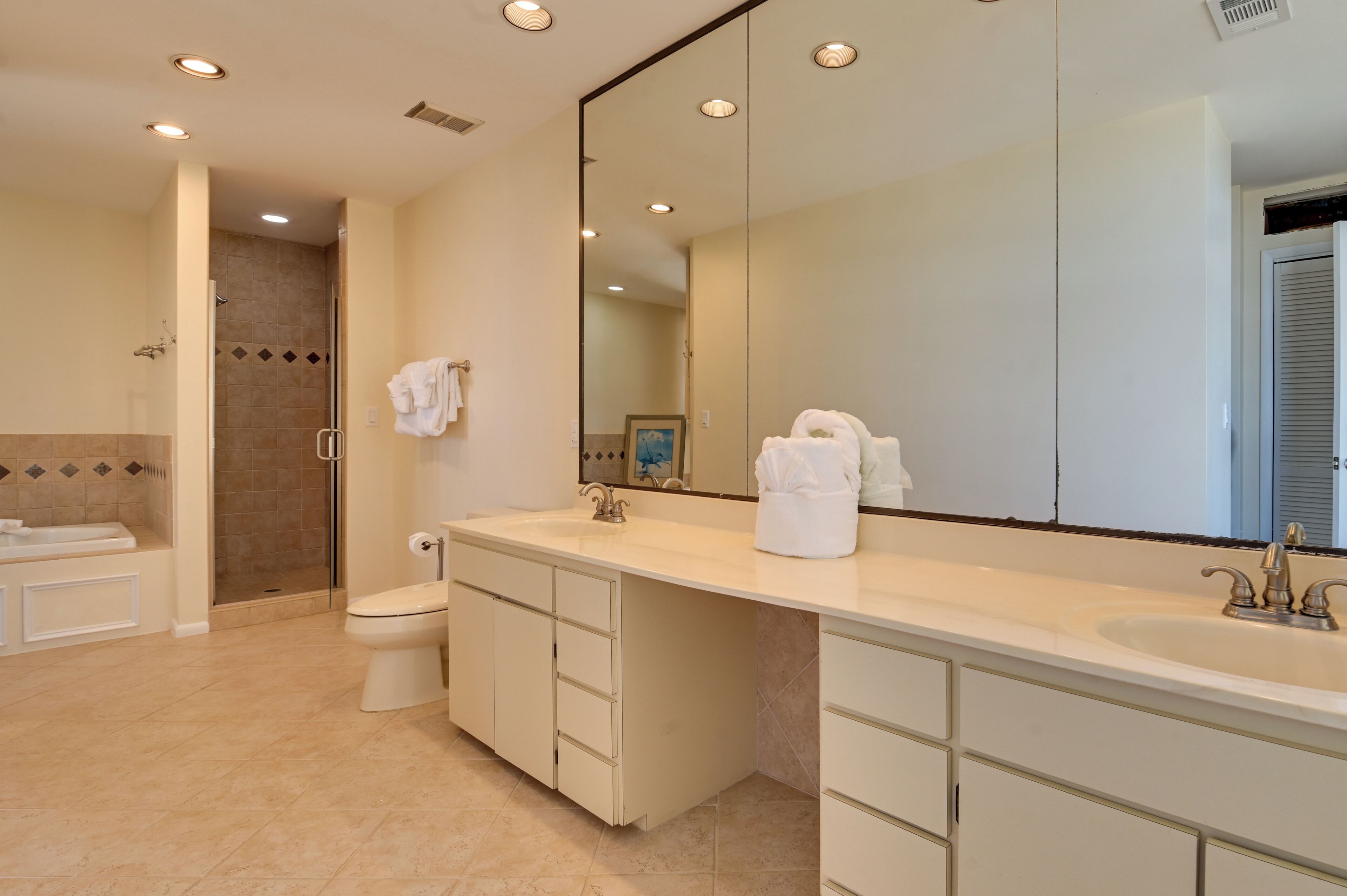 A modern bathroom with a large mirror, a bathtub, a toilet, and a shower area.